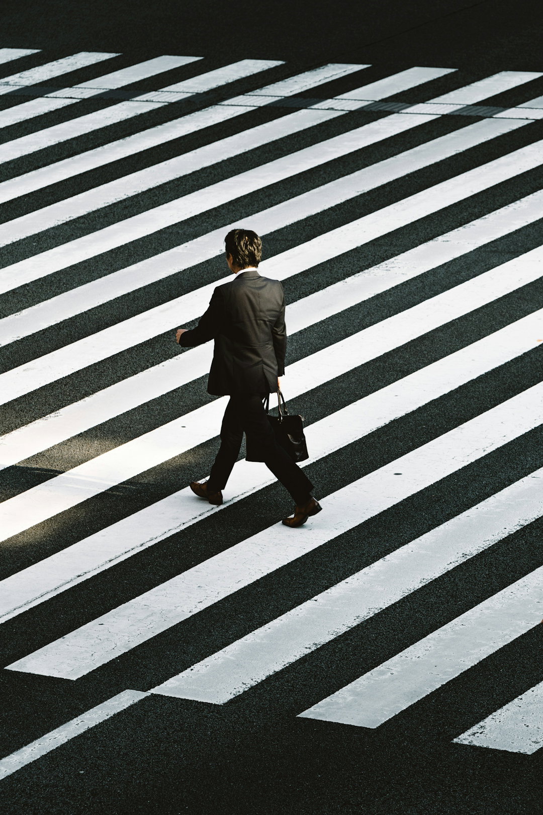 man-in-black-formal-suit-jacket-and-pants-carrying-black-bag-while-walking-on-pedestrian-lane-during-daytime.jpg man in black formal suit jacket and pants carrying black bag while walking on pedestrian lane during daytime